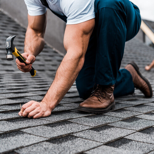 roofer installing shingles on a home